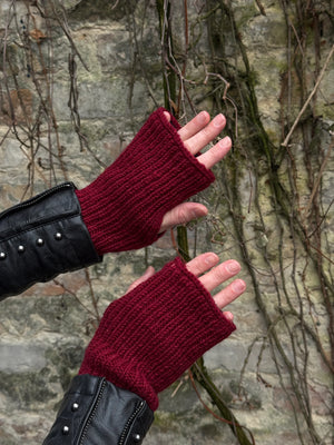 Nahaufnahme von zwei Händen präsentiert Handstulpen, Pulswärmer mit Daumenspalten aus Schurwolle Mahalaxim 55 in Kaminrot.