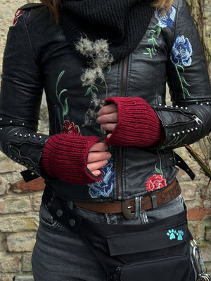 Nahaufnahme Hände: Model präsentiert Handstulpen, Pulswärmer mit Daumenspalten aus Schurwolle Mahalaxim 55 in Kaminrot.