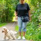 Wasserabweisende dunkelblaue Gassi-Tasche Brandenburg mit Flaschenhalter beim Spaziergang mit Hund im Grünen getragen