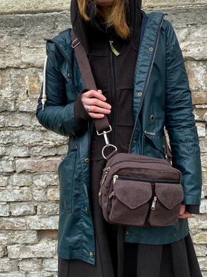 Ausschnittmodell, welches Gassi-Tasche Berlin Canvas Mahagonibraun in der Variante zum UmhĂ€ngen prĂ€sentiert.