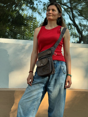 Braun-graue NIJENS Gassi-Tasche im Vintage-Look mit Lederdetails und Herz-Pfoten-Prägung, als Crossbody-Tasche getragen.