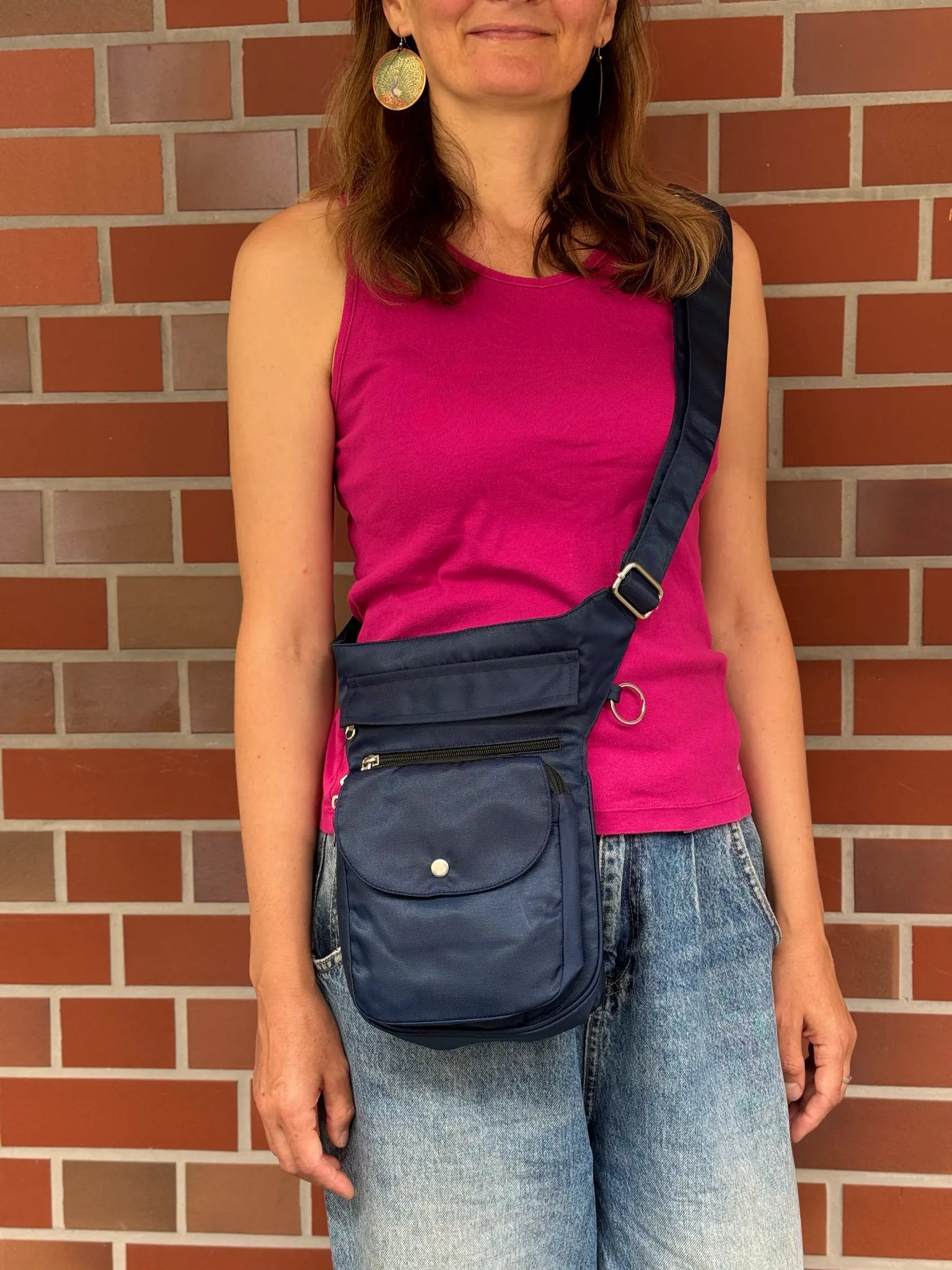 Frau trägt eine dunkelblaue wasserabweisende NIJENS Super-Hannover Gassi-Tasche als Crossbody. Praktische Hundetasche mit mehreren Fächern für Leckerlis, Handy und Zubehör.