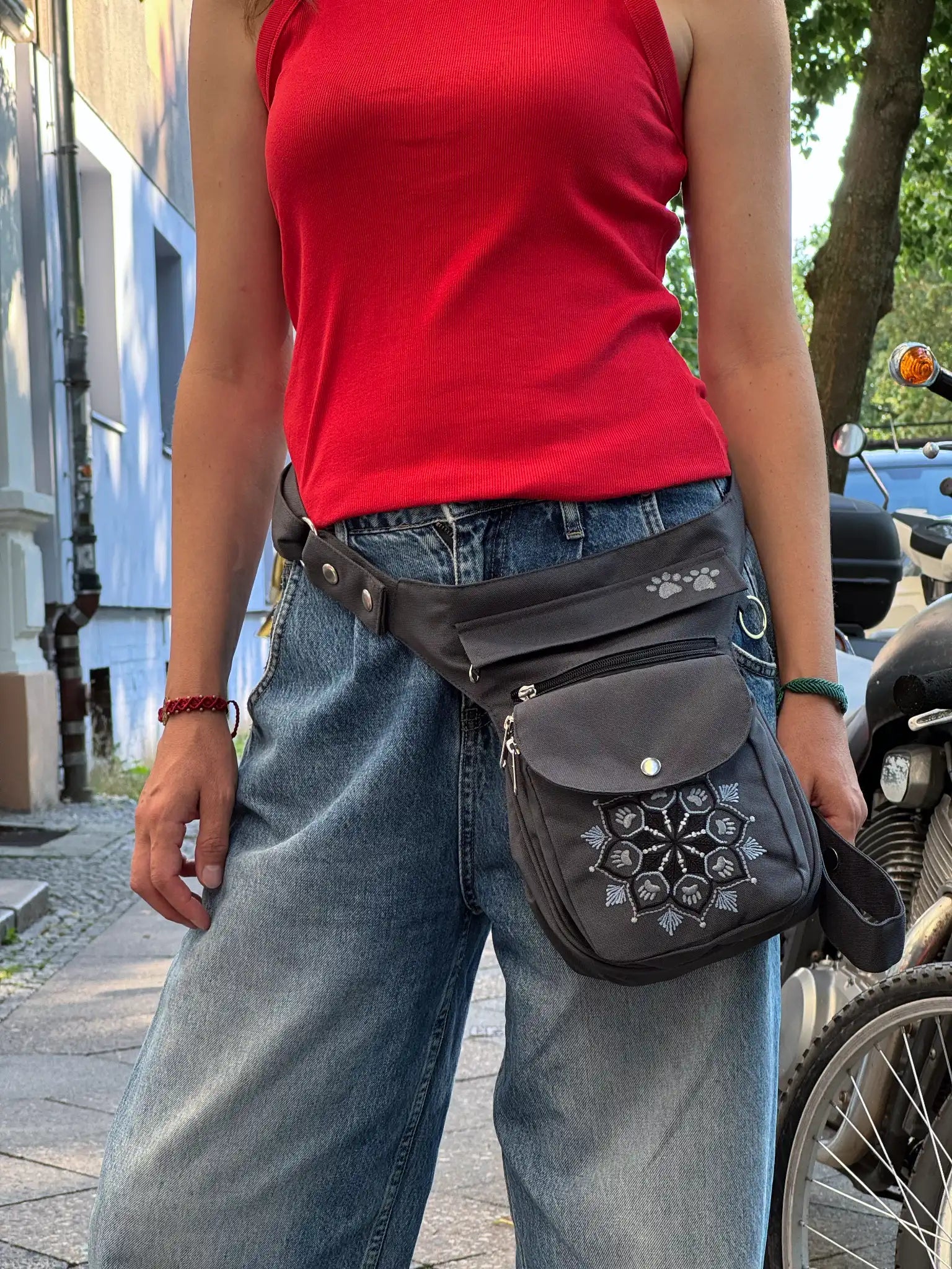 Graue NIJENS Gassi-Tasche mit Mandala- und Pfotenstickerei als Hüfttasche getragen – praktisch für Hundespaziergänge und Alltag.