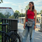 Frau trägt eine graue NIJENS Super-Hannover Gassi-Tasche mit Mandala-Stickerei als Crossbody beim Spaziergang in der Stadt.