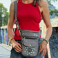 Frau trägt eine graue NIJENS Gassi-Tasche mit Mandala-Stickerei als Crossbody beim Spaziergang in der Stadt.