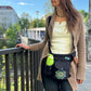 Frau trägt die wasserabweisende Nijens Gassitasche Brandenburg mit Mandala-Stickerei und Flaschenhalter als Crossbody auf einem Spaziergang in der Stadt.