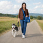 Frau mit Nijens Hüfttasche in Petrol und Sportschuhen spaziert mit einem Husky auf einem Feldweg in der Natur.