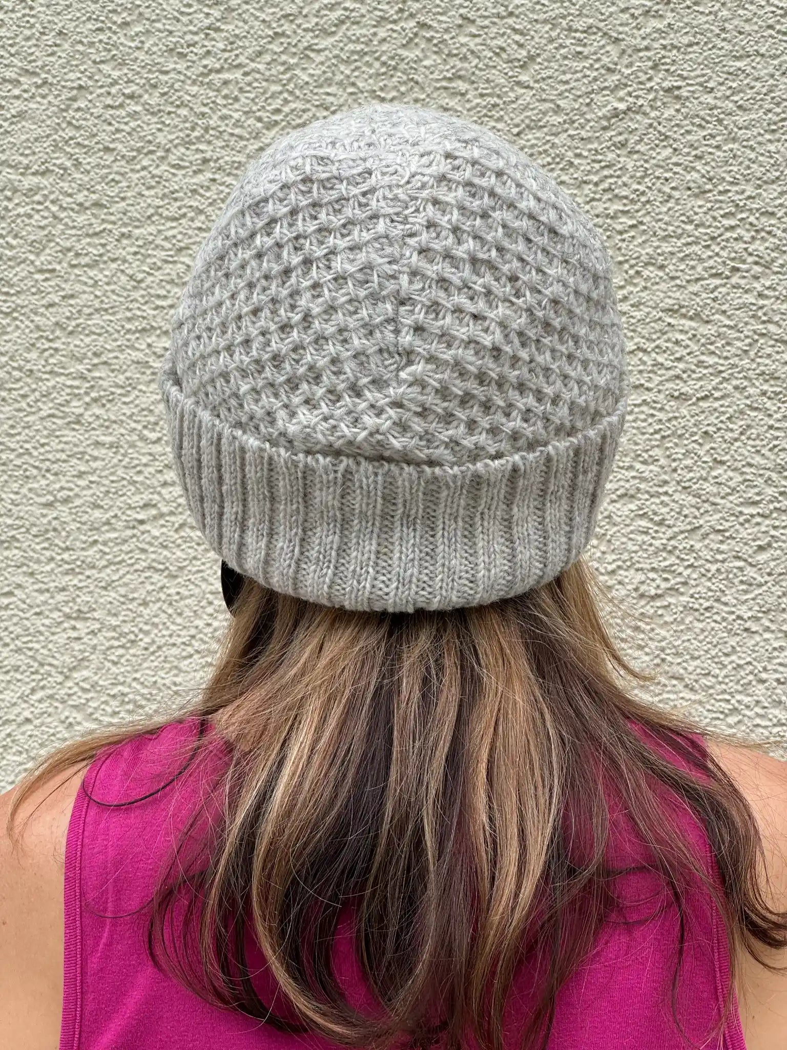 Rückansicht einer naturweißen Strickmütze aus Schurwolle mit strukturiertem Strickmuster