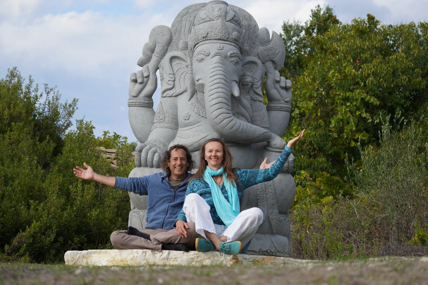 Amos und Tatiana sitzen lächelnd vor einer großen Ganesha-Statue – Symbol für Inspiration, Kreativität und Achtsamkeit hinter den Kulissen von Nijens.