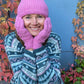 Weibliches Mützenmodell umringt mit herblichen Blättern und der Wollmütze, Strickmütze, Beanie-Mütze aus Schurwolle, Rosa, mit Umschlag und Fleeceeinsatz. Handgestrickte Handschuhe aus Schurwolle in Rosa mit Fleeceinlage und Zopfstrickmuster.