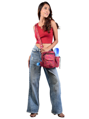 Studioaufnahme: Frau trägt eine Umhängetasche in kräftigem Rot mit gelben, blauen und orangefarbenen Pfoten – praktische Tasche mit mehreren Fächern.