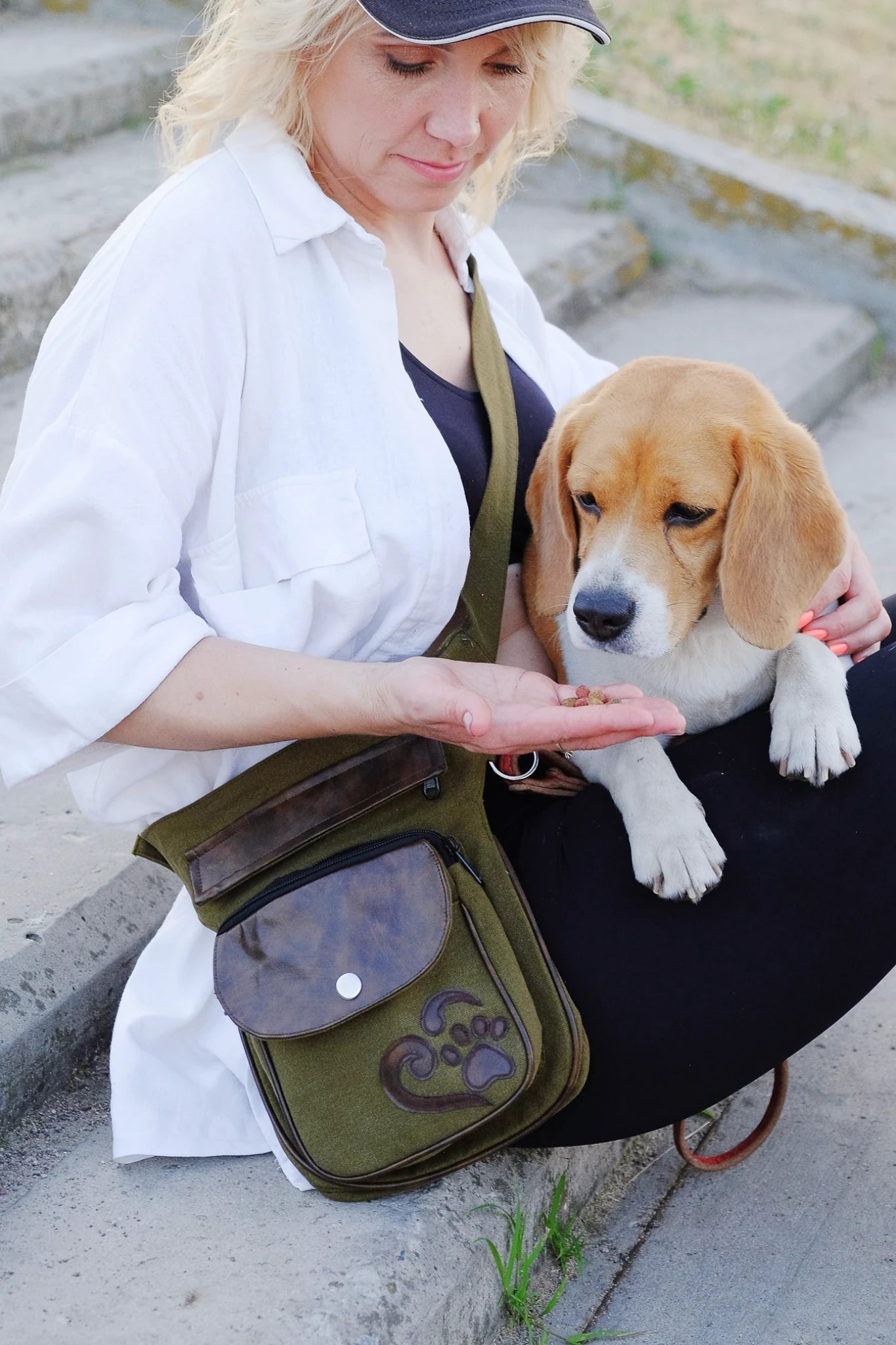 Frau mit olivgrüner Nijens Gassi-Tasche aus Canvas mit Pfote-Herz-Applikation gibt einem Beagle ein Leckerli.