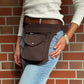Eine Frau präsentiert eine Bauchtasche aus robustem Baumwollstoff in Schokobraun. 
