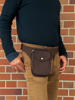 Model präsentiert kleine Bauchtasche aus robustem Baumwollstoff in Schokobraun. 