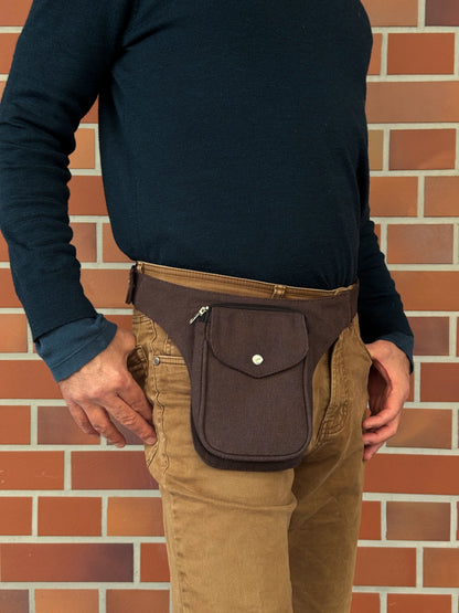 Model präsentiert kleine Bauchtasche aus robustem Baumwollstoff in Schokobraun. 