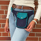 Eine Frau präsentiert Bauchtasche aus robustem Baumwollstoff in türkis-blau mit Muster und kleinen Pfoten-Print. 