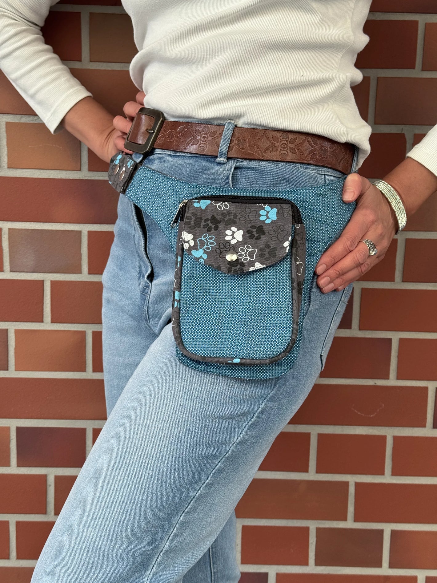 Model präsentiert kleine Bauchtasche aus robustem Baumwollstoff in grau, hellblau mit Muster und großen Pfoten-Print. 
