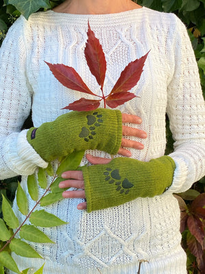 Nahaufnahme Hände: Modell mit Pulswärmer, Armstulpen mit Zwei-Pfoten-Stickerei aus Schurwolle, Hellgrün und Fleeceeinsatz. An der Seite gibt es einen Spalt für den Daumen.