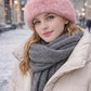 Rosa Kunstfell-Wintermütze auf Model im urbanen Winteroutfit mit Mantel und Schal