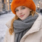 Model trägt orange Kunstfell-Wintermütze im urbanen Winterlook mit Schal