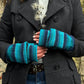 Nahaufnahme Hände: Model präsentiert fingerfreie Handschuhe aus Wolle gestreift in Blautönen, welche sich mit einer Fingerkappe zu Fäustlingen umwandeln lassen.
