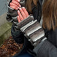 Nahaufnahme Hände: Model präsentiert fingerfreie Handschuhe aus Wolle gestreift in Braun, Grautöne, welche sich mit einer Fingerkappe zu Fäustlingen umwandeln lassen.