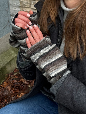 Nahaufnahme Hände: Model präsentiert fingerfreie Handschuhe aus Wolle gestreift in Braun, Grautöne, welche sich mit einer Fingerkappe zu Fäustlingen umwandeln lassen.