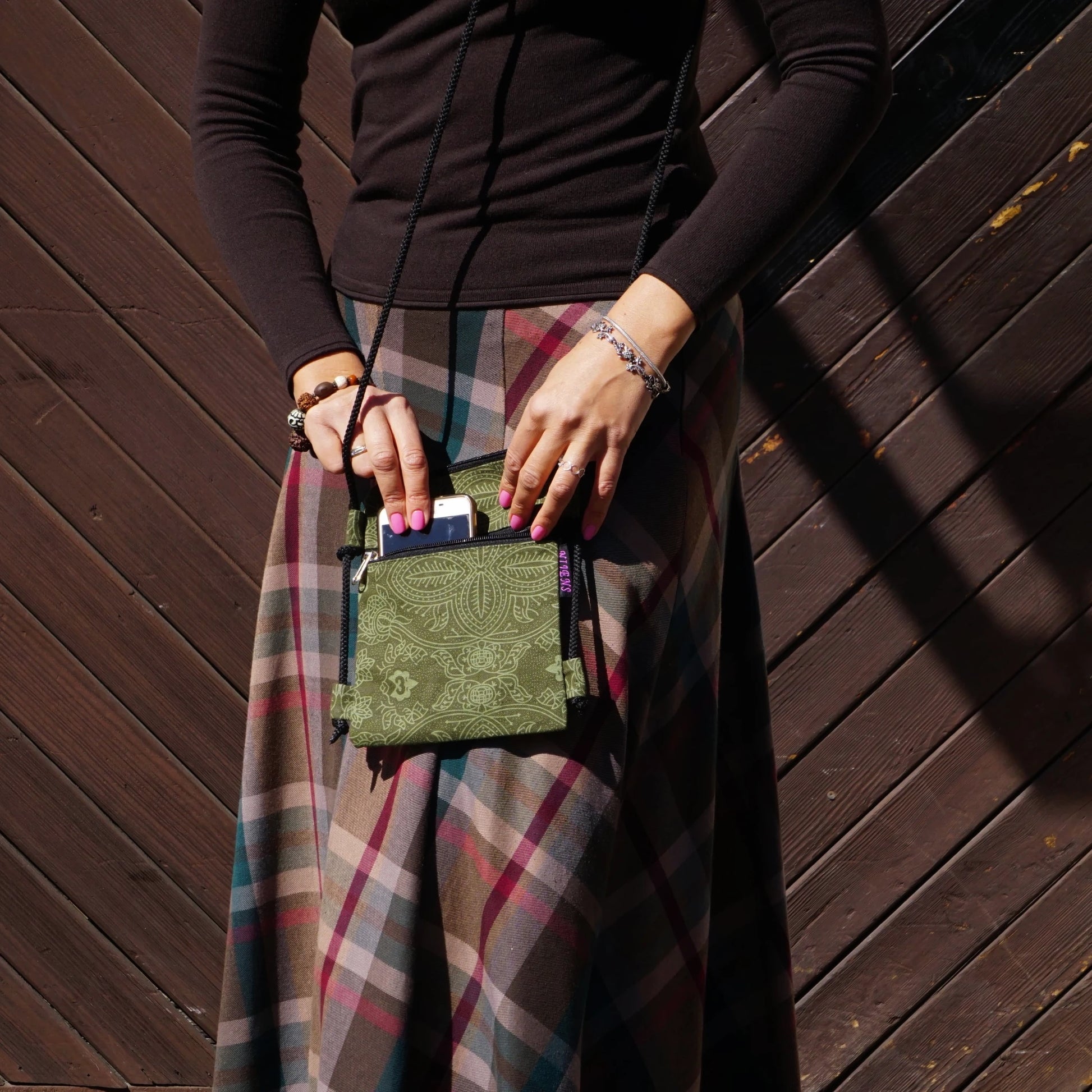Kleine Handytasche Smolly in Grün mit feinem Muster, getragen als Crossbody-Tasche.