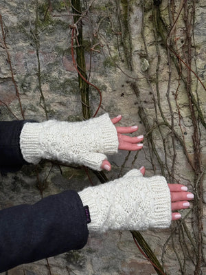 Nahaufnahme Hände: Das Model präsentiert Gestrickte Pulswärmer, Stulpen mit Daumen aus Wolle Weiß.