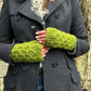 Nahaufnahme Hände: Das Model präsentiert Gestrickte Pulswärmer, Stulpen mit Daumen aus Wolle Grün.