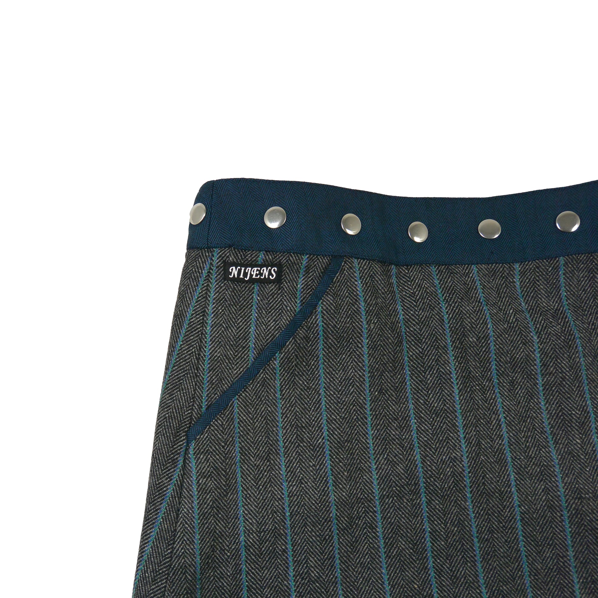 Detailaufnahme der grauen Tweedseite mit blauen Streifen und silbernen Druckknöpfen von Nijens