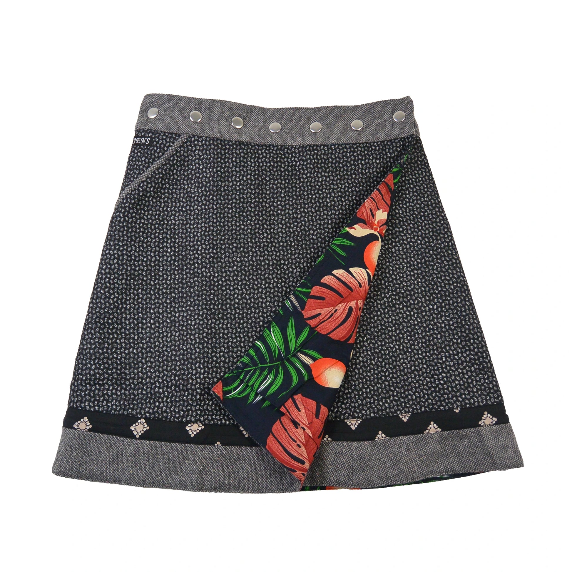 Frontseite des Wenderocks aus Tweed mit grauem Muster und farbenfroher Innenseite mit Blättern und Früchten. Nijens Shop.