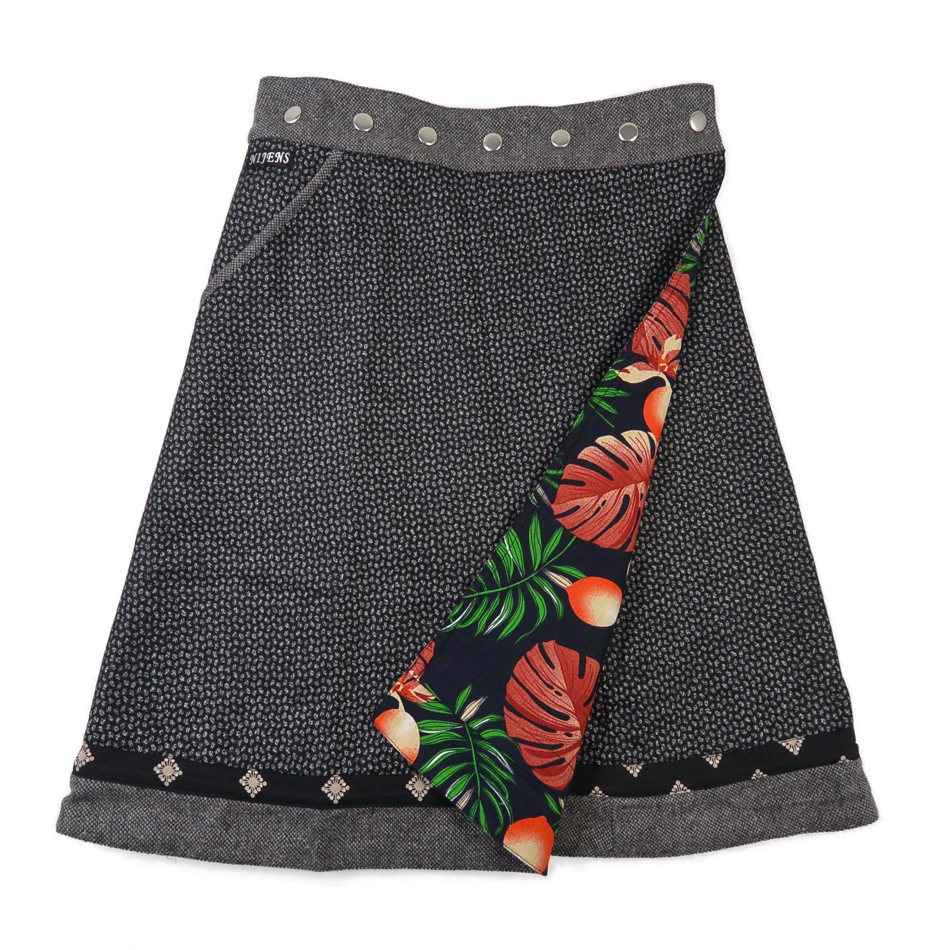 Frontseite des Wenderocks aus Tweed mit grauem Muster und farbenfroher Innenseite mit Blättern und Früchten