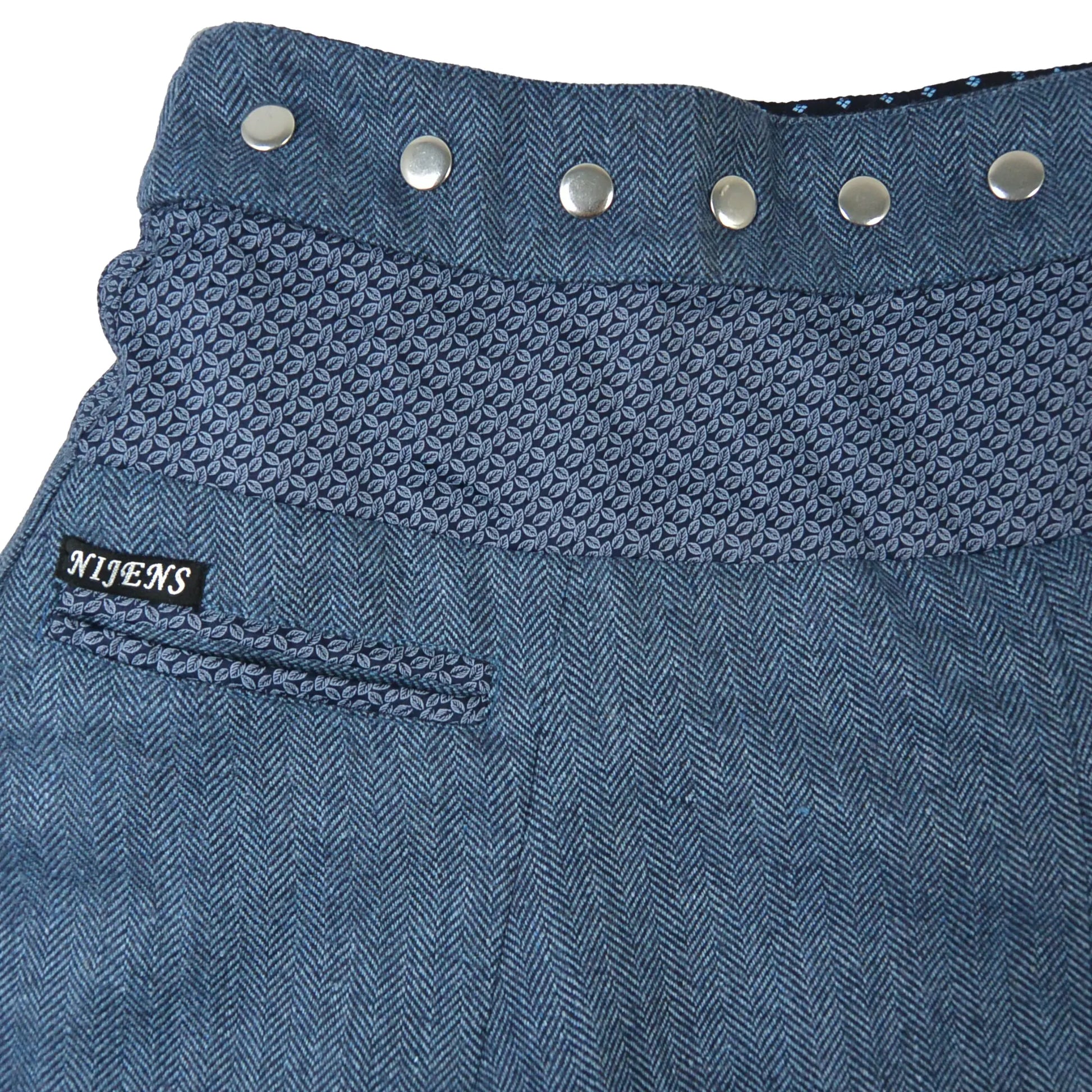 Detailaufnahme des Wenderocks: Blaue Tweedstruktur, gemusterte Innenseite und feine Stoffdetails der reversiblen Winterrock-Designs.