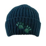 Warme Beanie aus 100 % Schurwolle in Dunkelpetrol mit zwei grünen gestickten Hundepfoten auf dem Umschlag.