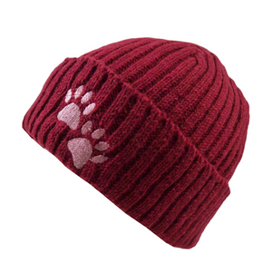 Warme Beanie aus 100 % Schurwolle in Weinrot mit zwei rosafarbenen, gestickten Hundepfoten auf dem Umschlag. Seitenansicht.