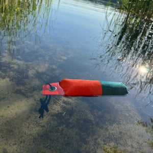 Wurf-Dummy für Hunde in Orange und Dunkelgrün mit Holzgriff treibt auf der Wasseroberfläche.
