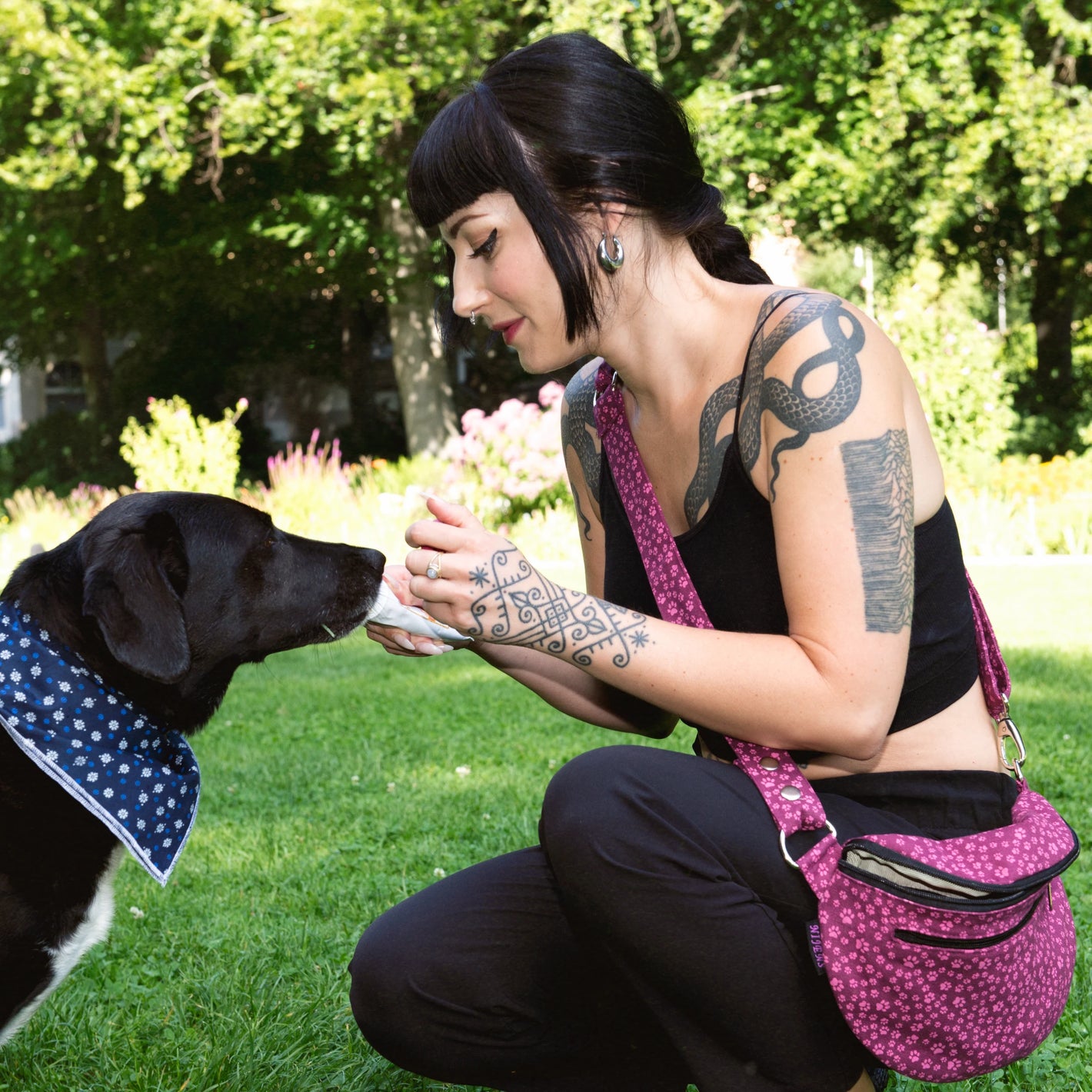 Model mit Hund im Park präsentiert Bauchtasche sowie Crossbodybag aus Canvas in Magenta, mit rosafarbenen kleinen Pfötchen. Großes Hauptfach mit Reißverschlussfach vorne. 