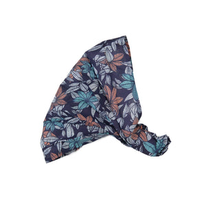 Nijens Stoff-Haarband in Dunkelblau mit Blattmuster in Türkis, Rostorange und Weiß, seitlich liegend vor weißem Hintergrund