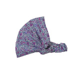 Nijens Stoff-Haarband in Lavendel mit kleinem Blumenmuster in Türkis, Rostorange und Weiß, seitlich liegend vor weißem Hintergrund