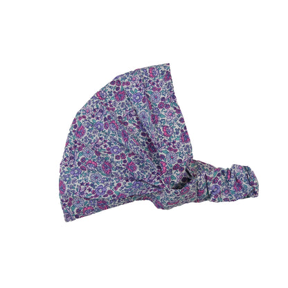 Nijens Stoff-Haarband in Lavendel mit kleinem Blumenmuster in Türkis, Rostorange und Weiß, seitlich liegend vor weißem Hintergrund