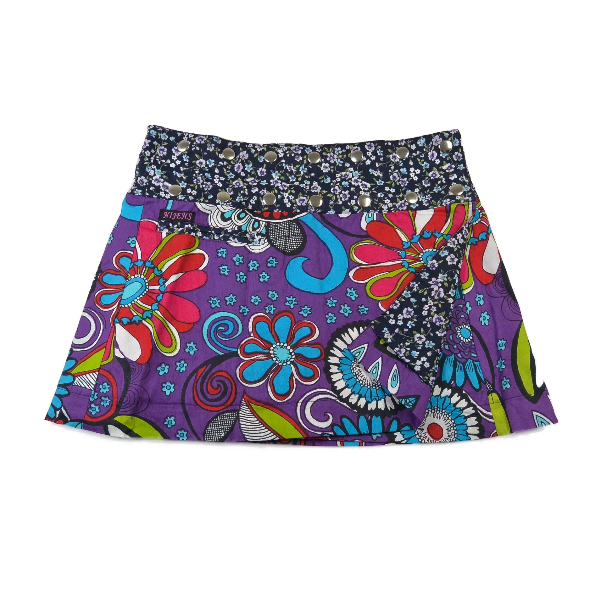 Wendeseite mit auffälligem Retro-Blumenmuster in kräftigem Violett und Himmelblau – ergänzt durch einen dunklen Blümchenbund mit silbernen Druckknöpfen.