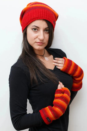 Model präsentiert Armstulpen, Pulswärmer aus Schurwolle, gestreift in Rot, Orangetönen mit Daumen und Innenfutter aus Fleece. Auf dem Kopf trägt sie eine long Beanie Mütze Wollmütze aus Schurwolle Gestreift - Satti Hat C-23 in Rot, Orangetönen.