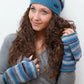 Model präsentiert eine gestreifte long Beanie Mütze aus Schurwolle in Grau, Blautönen. An den Händen trägt sie fingerfreie Handschuhe aus Wolle gestreift in Blautönen, welche sich mit einer Fingerkappe zu Fäustlingen umwandeln lassen. 