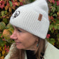 Frau trägt weiße Nijens Angora Beanie Marseille mit Pfote-&-Herz-Stickerei beim herbstlichen Spaziergang