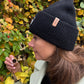 Frau trägt schwarze Nijens Angora Beanie Marseille mit Pfote-&-Herz-Stickerei beim herbstlichen Spaziergang