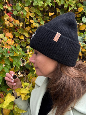 Frau trägt schwarze Nijens Angora Beanie Marseille mit Pfote-&-Herz-Stickerei beim herbstlichen Spaziergang
