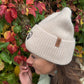 Frau trägt beige Nijens Angora Beanie Marseille mit Pfote-&-Herz-Stickerei beim herbstlichen Spaziergang