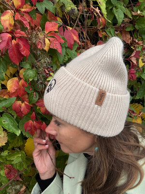 Frau trägt beige Nijens Angora Beanie Marseille mit Pfote-&-Herz-Stickerei beim herbstlichen Spaziergang