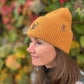 Frau trägt orange Nijens Angora Beanie Marseille mit Pfote-&-Herz-Stickerei beim herbstlichen Spaziergang